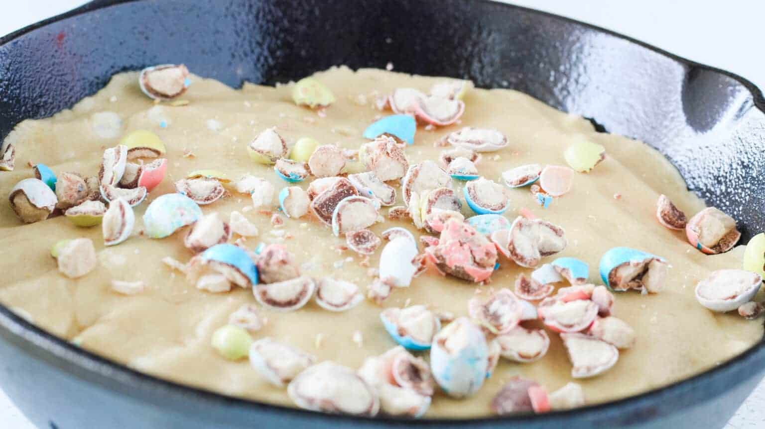 malted milk eggs crushed and placed on top of easter skillet cookie dough in skillet