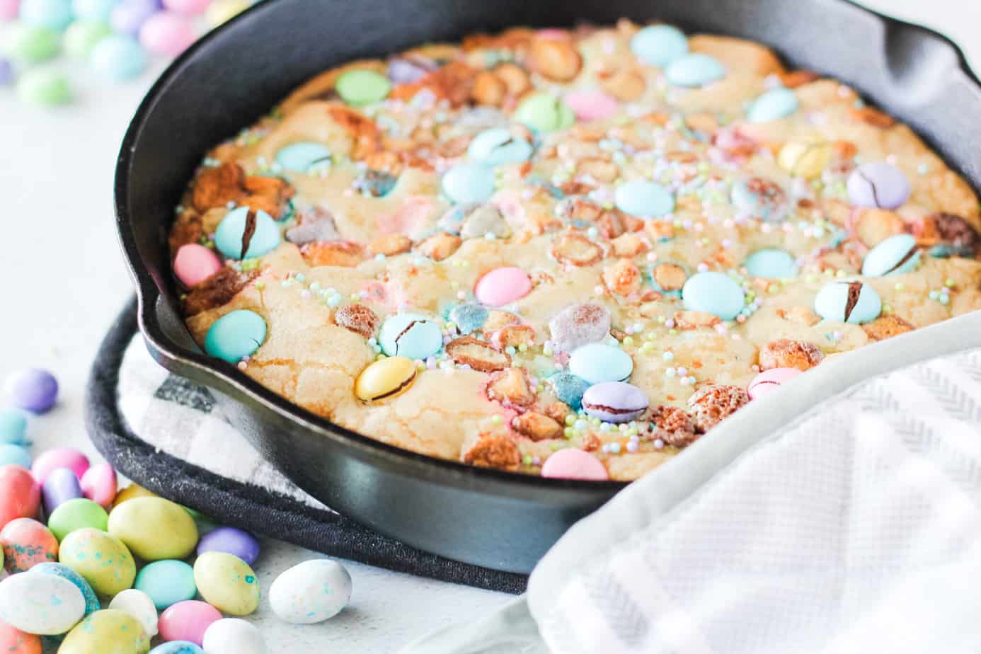 Easter Skillet Cookie recipe made in a cast iron skillet with M&M's on the counter