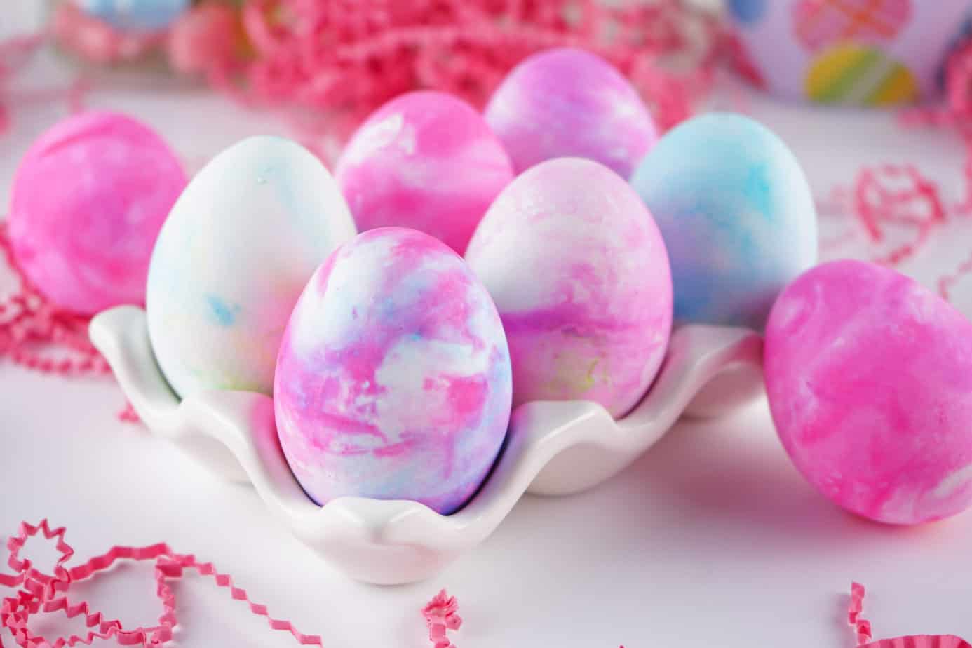 Pink, purple, and blue Tie-dyed Cool Whip Easter Eggs in a white ceramic egg holder. 
