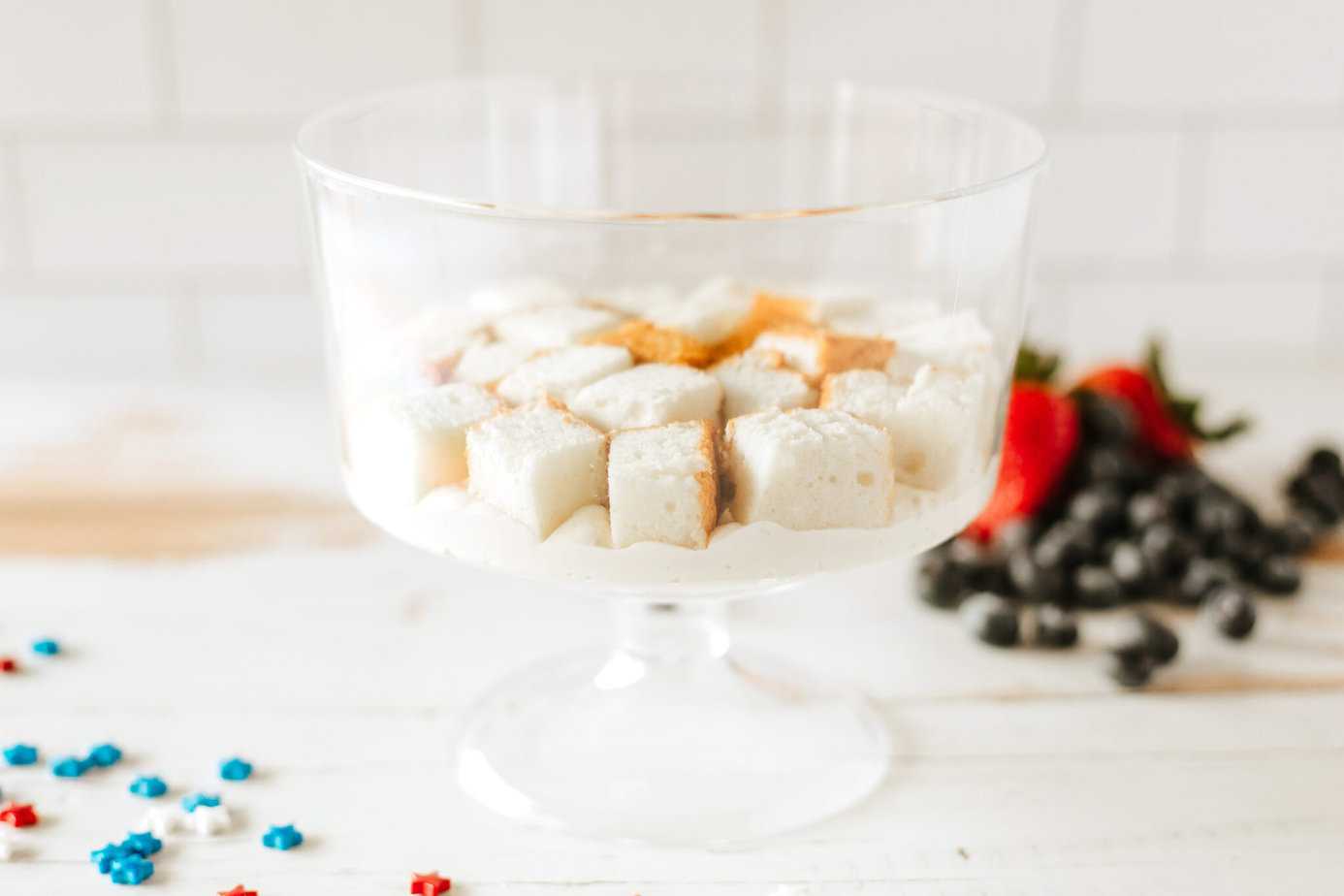 layers of cream cheese mixture with cake on top in trifle dish