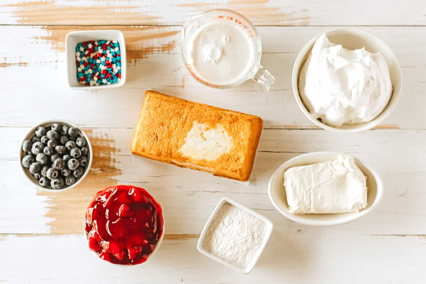 Red, White and Blue Trifle ingredients in bowls on a white wood surface