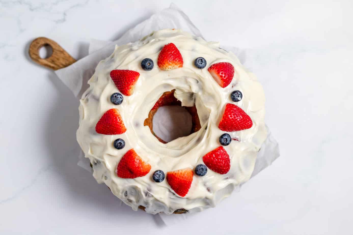 cream cheese glaze on pound cake with strawberries and blueberries on top