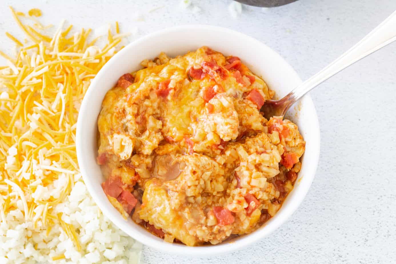 chicken taco casserole served in a white bowl with a spoon in the bowl.