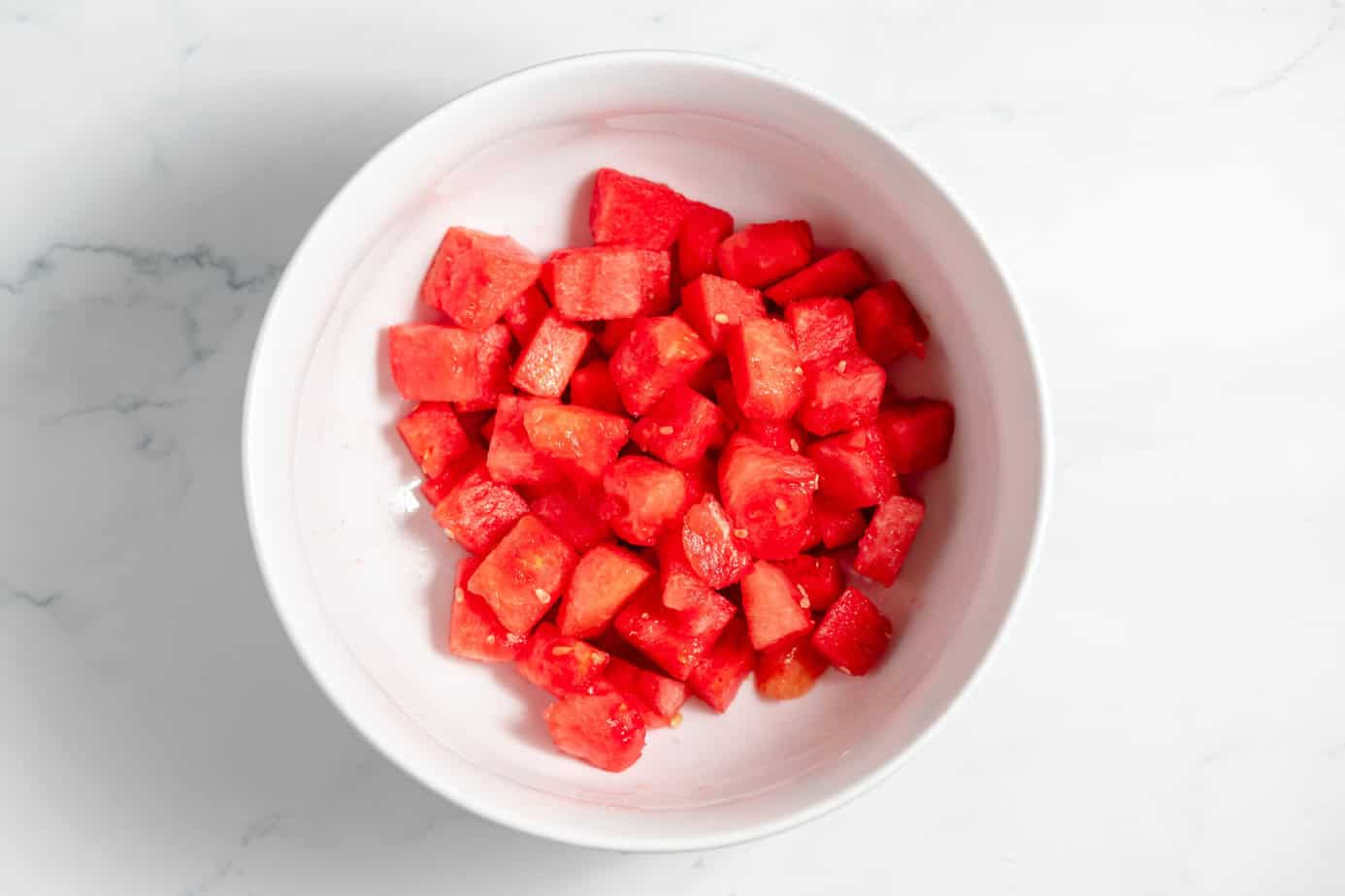 cubed watermelon in a white bowl