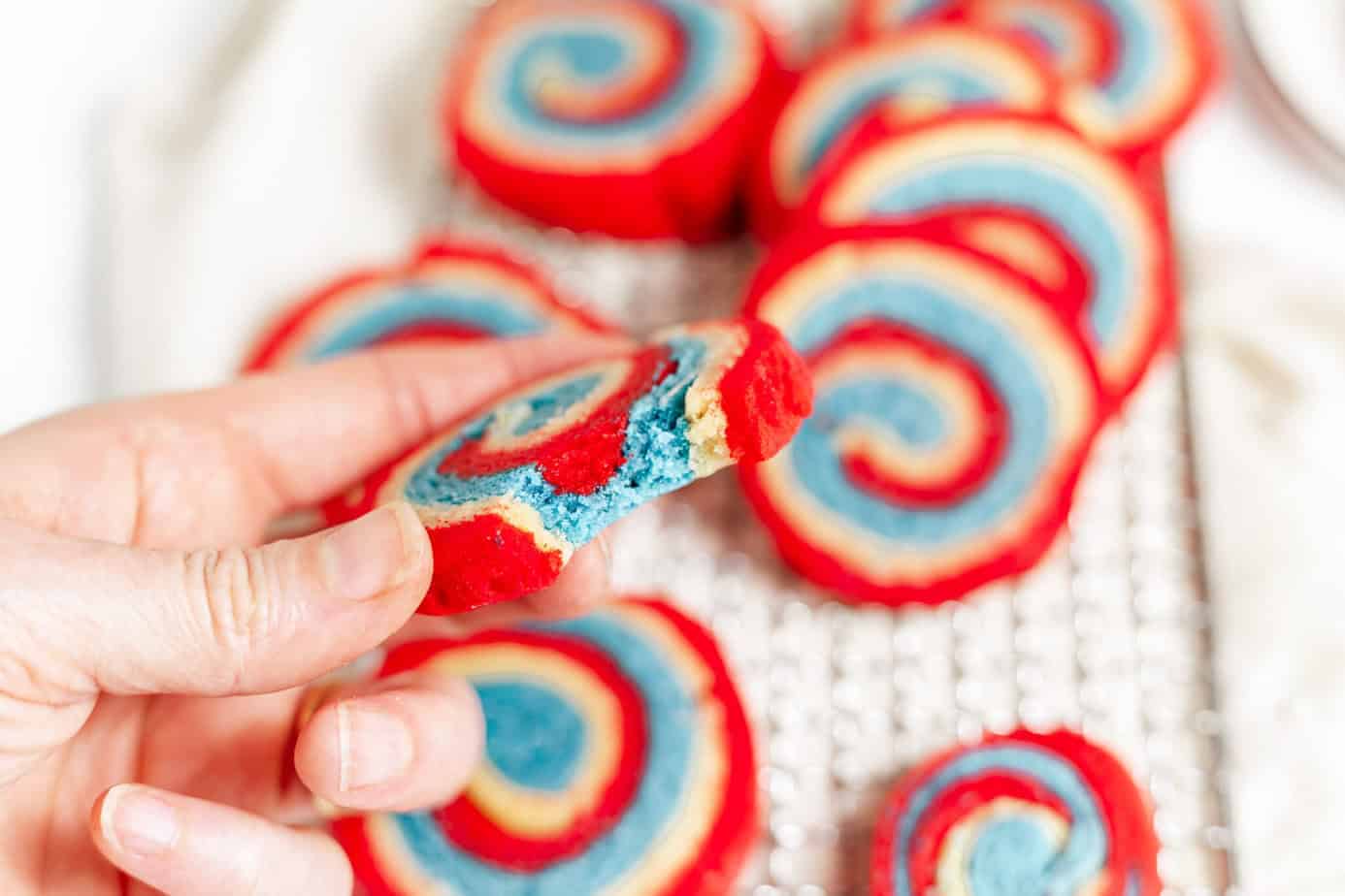 baked red white and blue pinwheel cookies - one with a bite missing