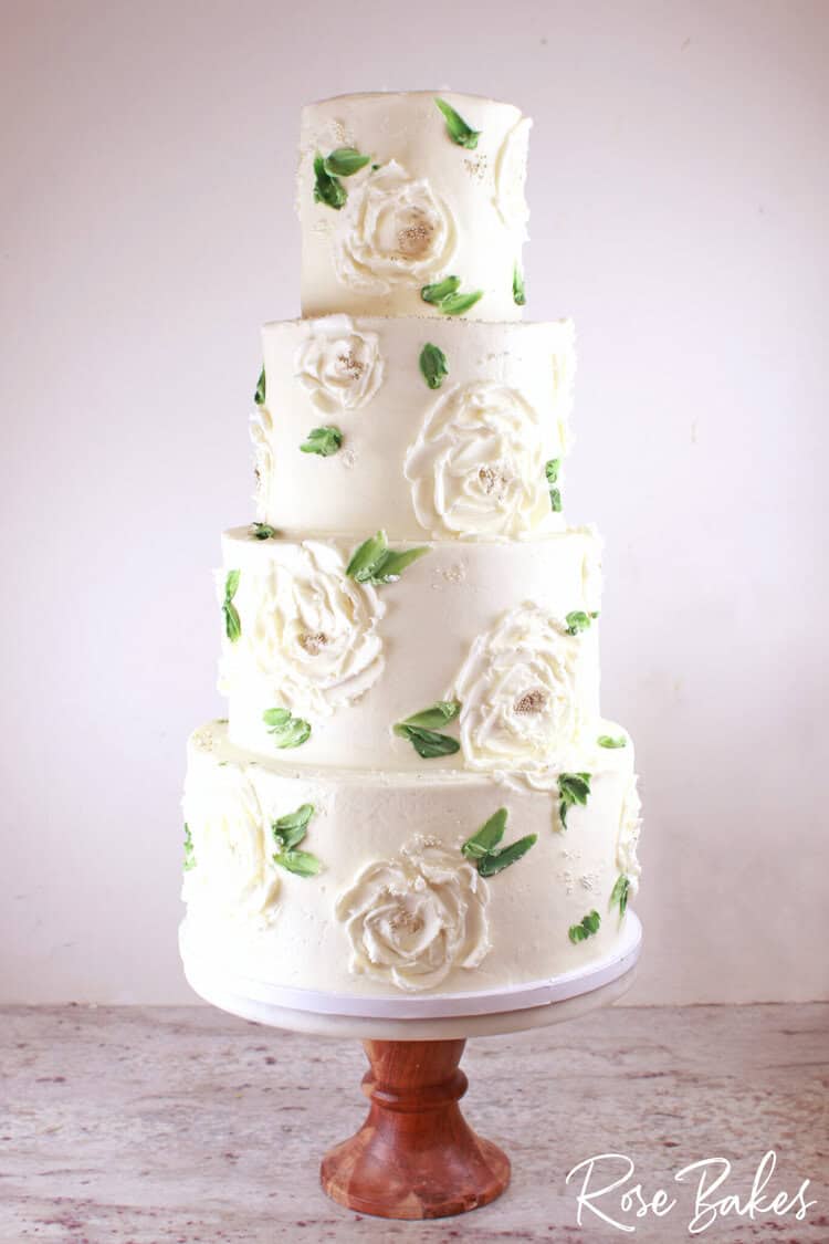 Buttercream palette painted magnolias wedding cake on a wooden stand