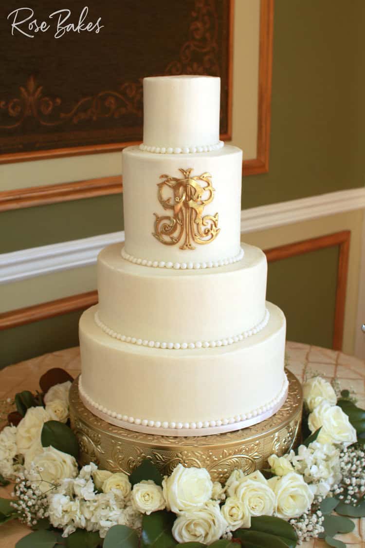 classic white buttercream wedding cake with gold monogram and fondant pearls