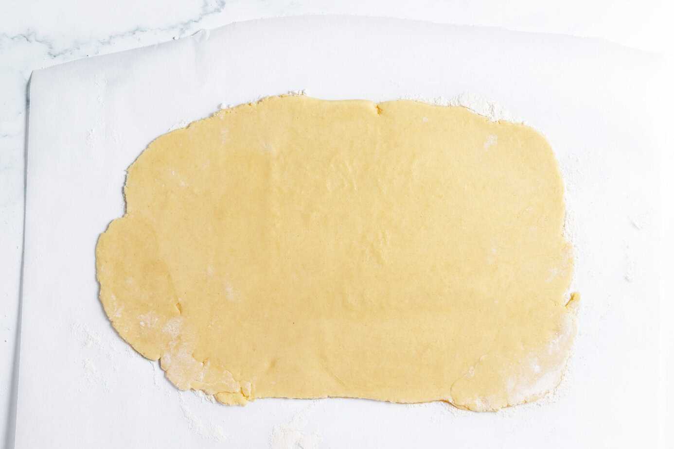 cookie dough rolled out on parchment paper