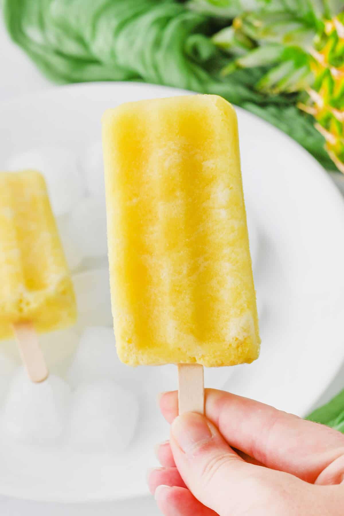 pina colada popsicle being held over a plate