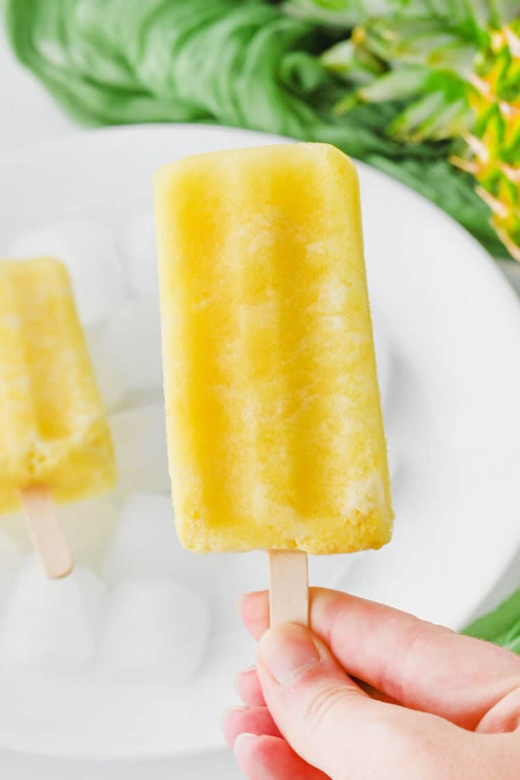 pina colada popsicle being held over a plate