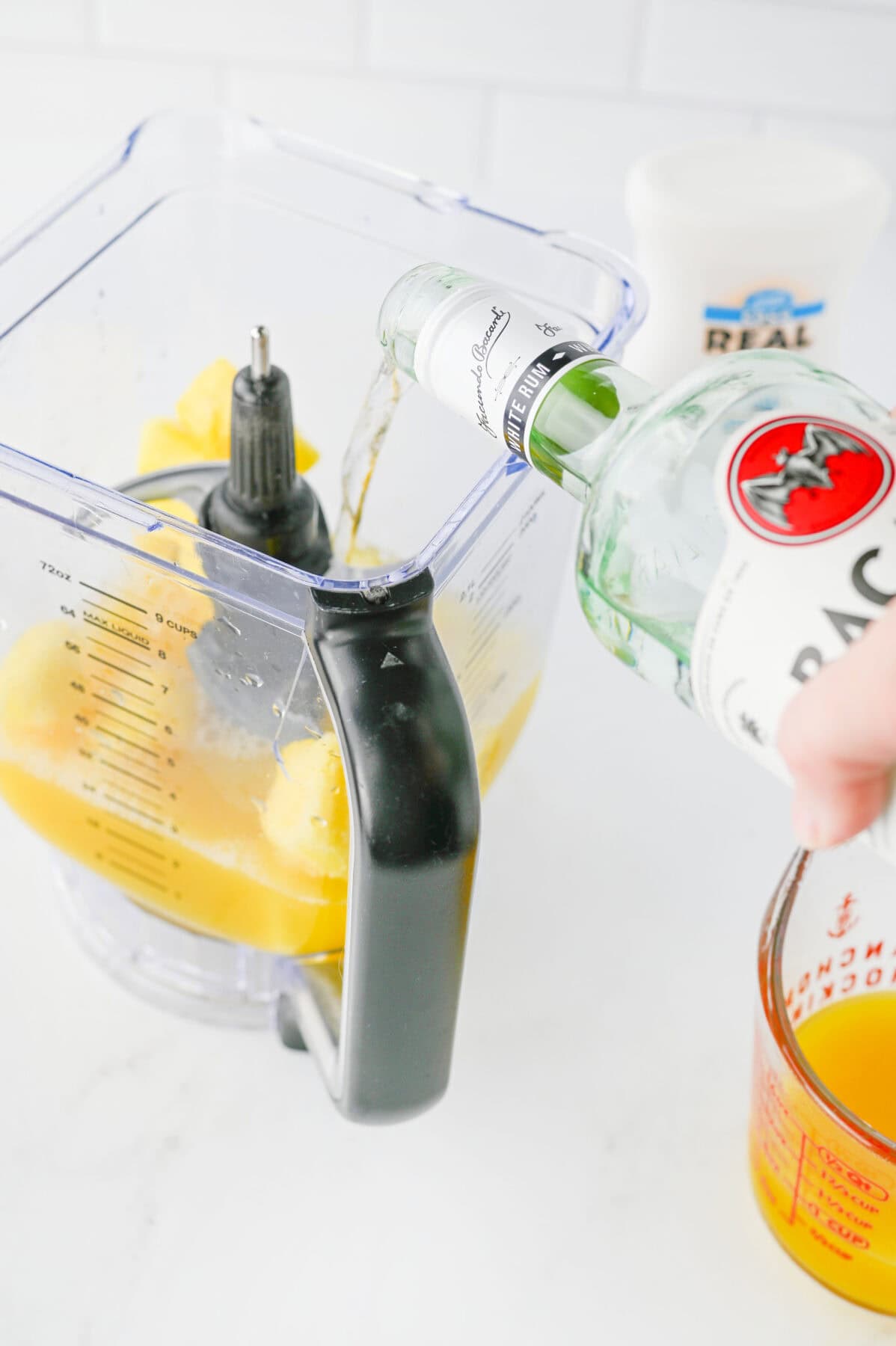 adding rum to the blender with other pina colada ingredients.