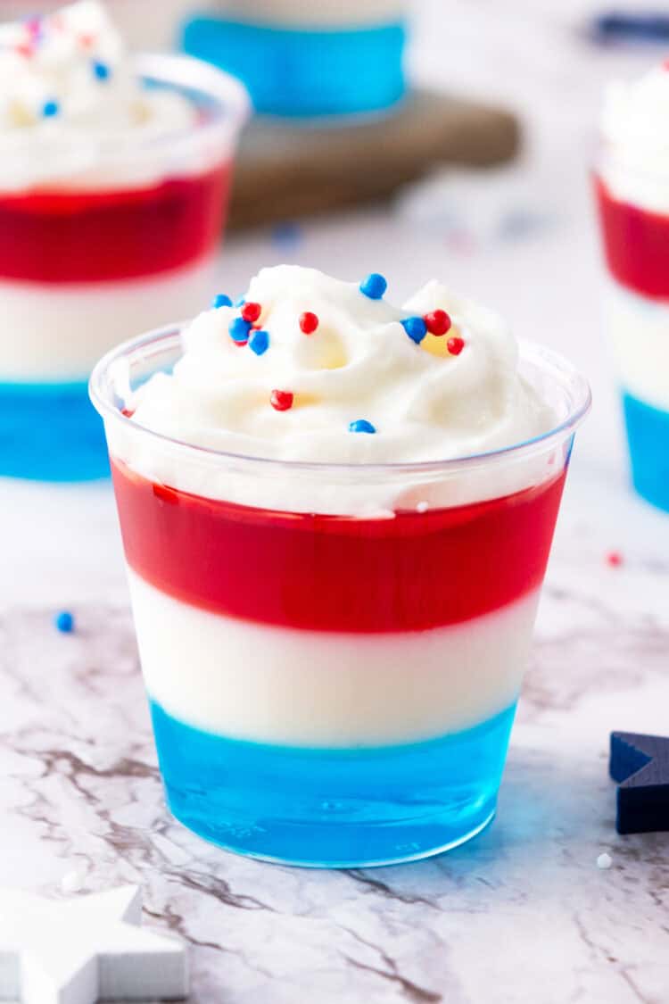 red white and blue jello shots on a white surface with patriotic sprinkles