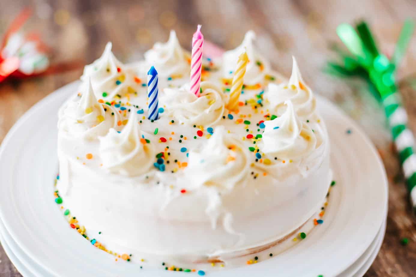 air fryer cake on a stack of white plates decorated as a birthday cake with candles and sprinkles