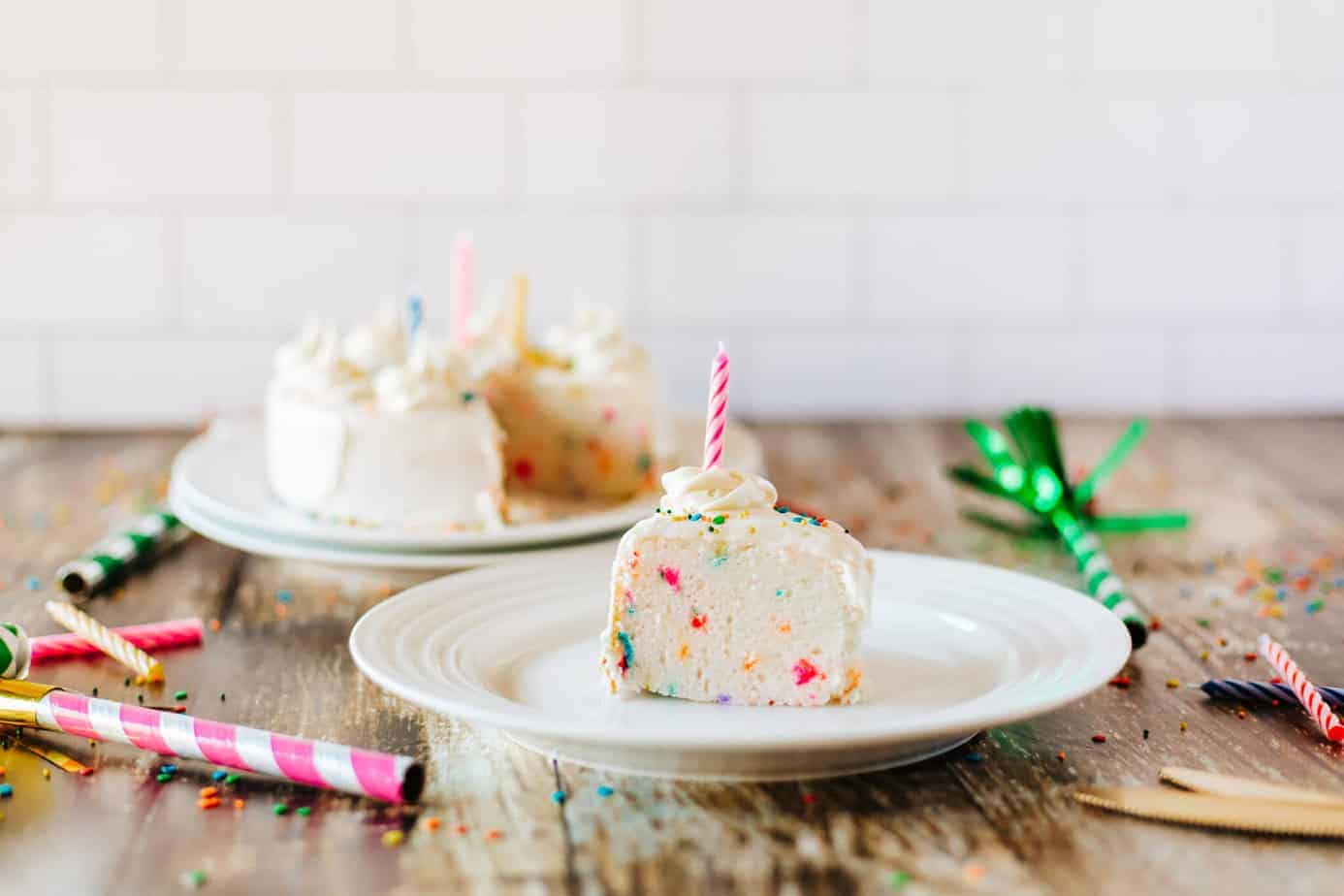 slice of air fryer cake with sprinkles and party horns next to it on a wooden surface