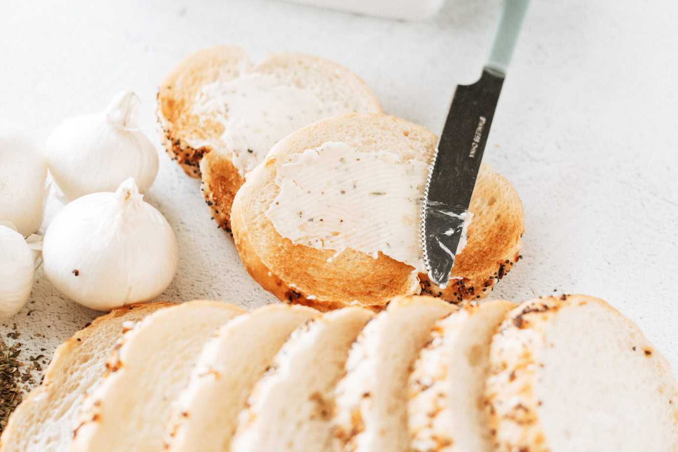 garlic butter spread on toast with a butter knife and more sliced bread next to it