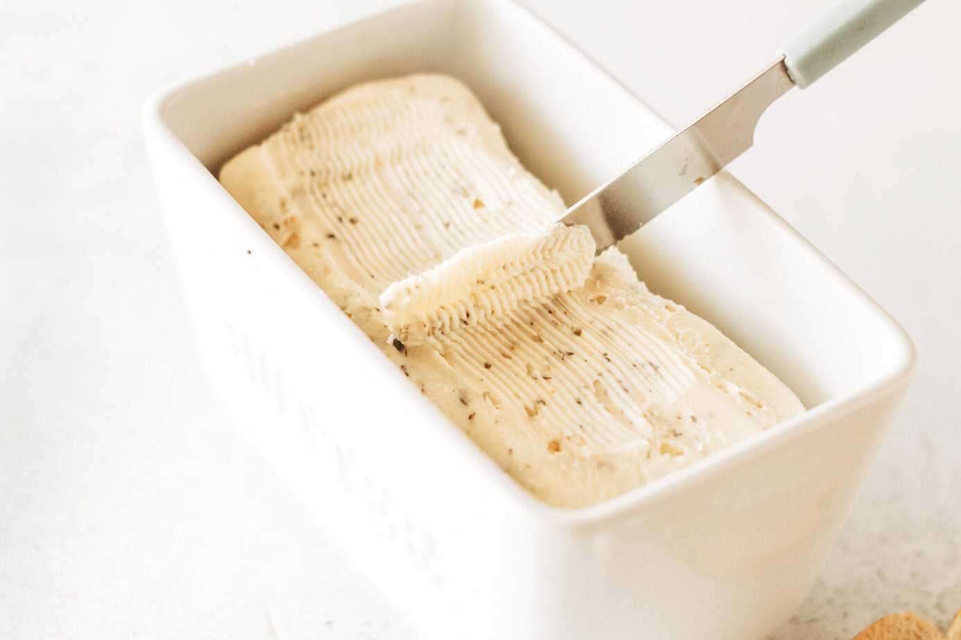 fresh homemade garlic and herbs butter in a dish with a butter knife