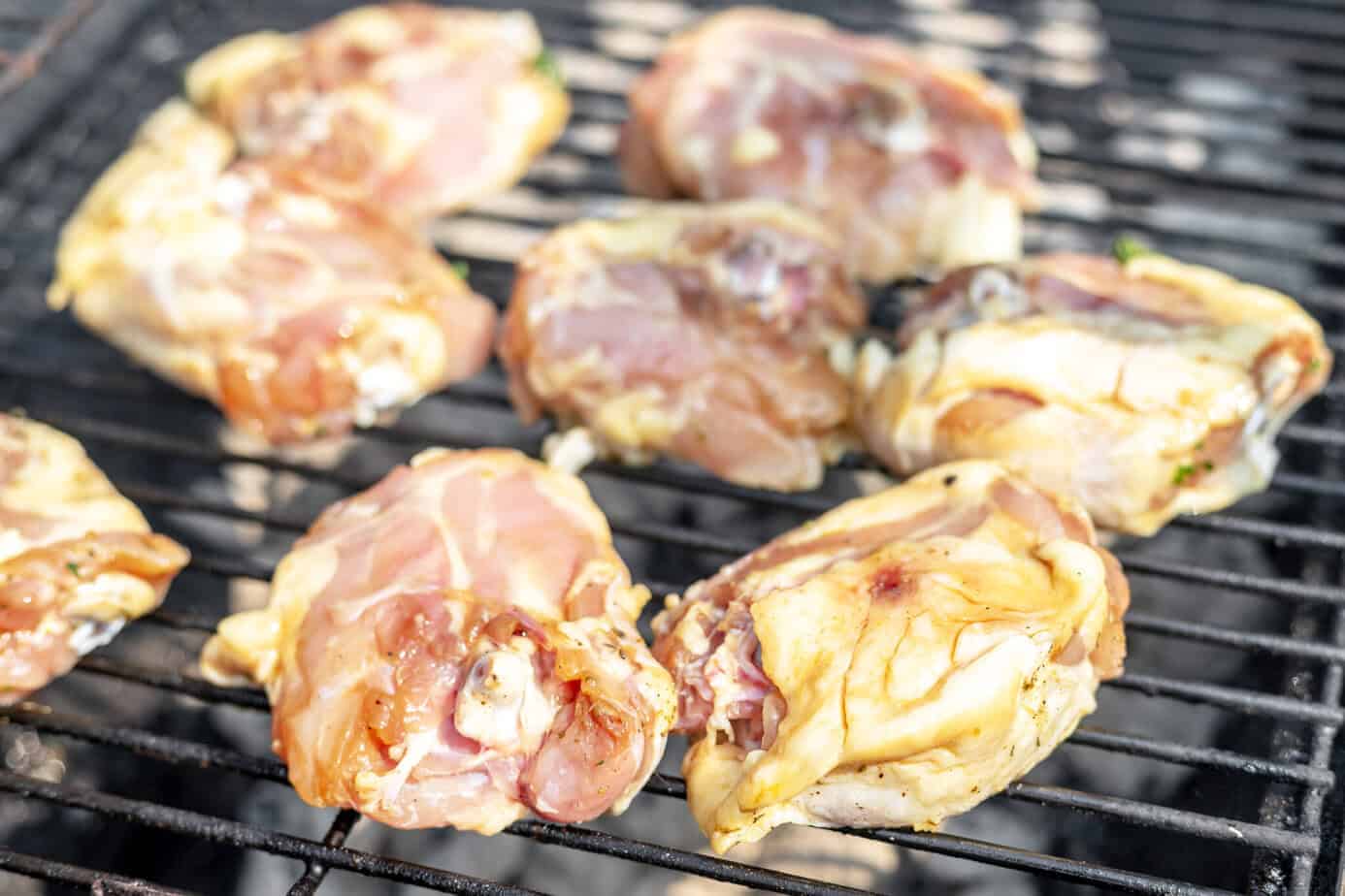 raw marinated chicken thighs on a grill