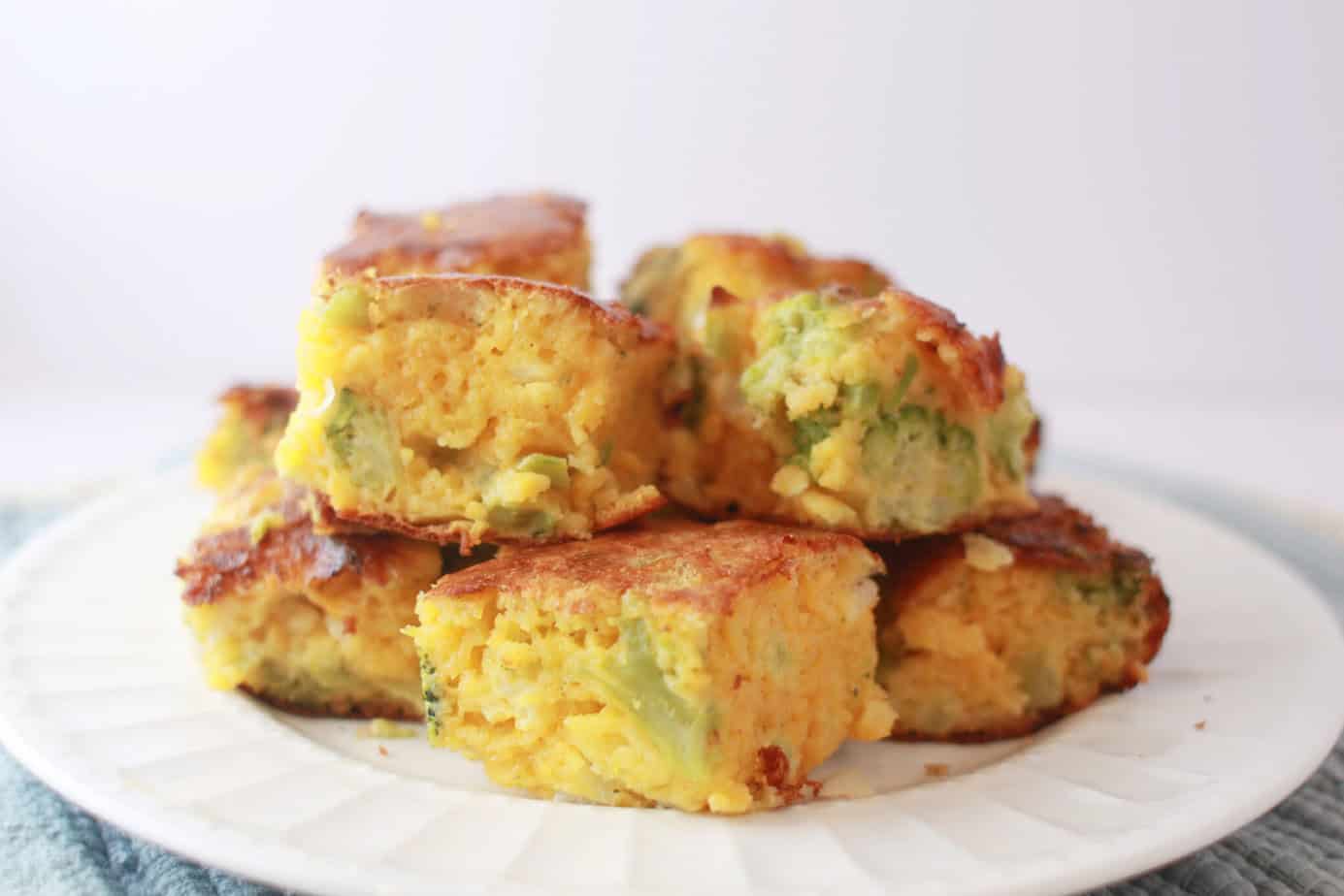 squares of cheesy broccoli cornbread stacked on a white plate