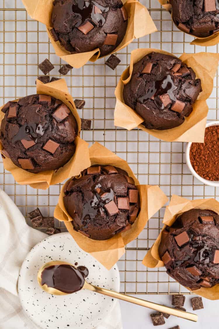 olympic village chocolate muffins on a wire rack with ganache and cocoa powder and chocolate chunks