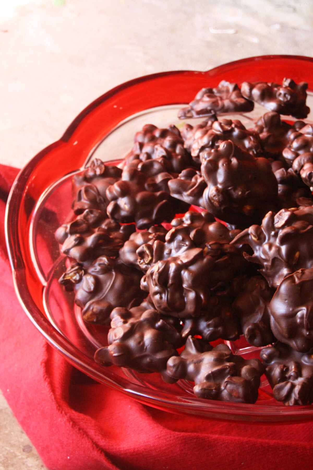 chocolate peanut clusters in a christmas bowl on a red cloth