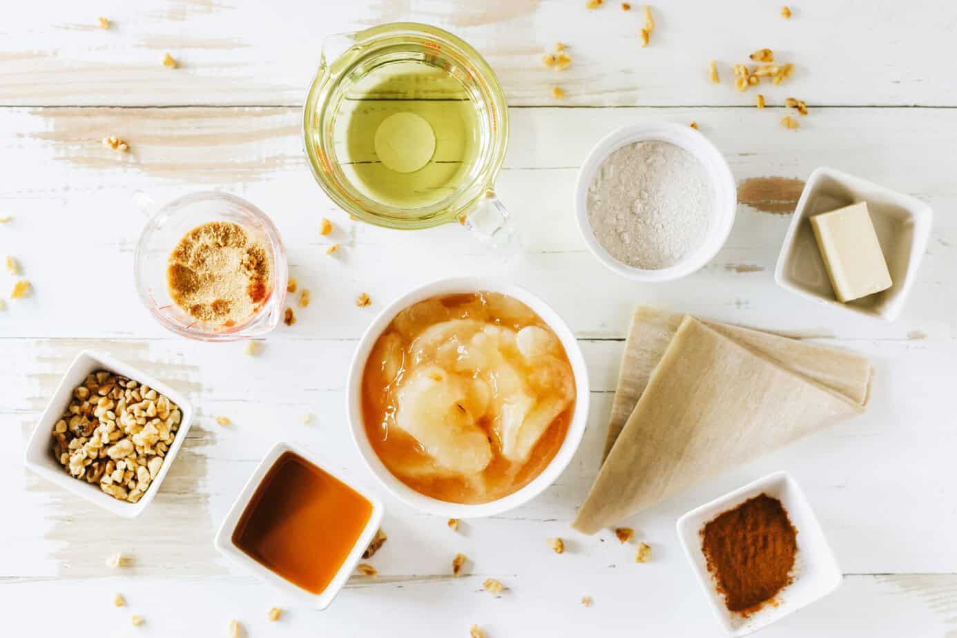 apple pie egg roll ingredients on a white wooden surface in individual bowls
