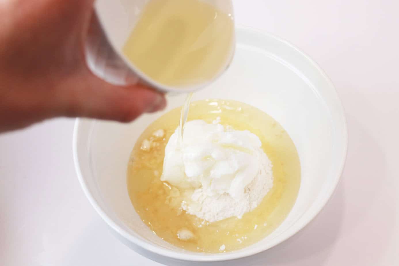 pouring oil into a mixing bowl with flour and shortening