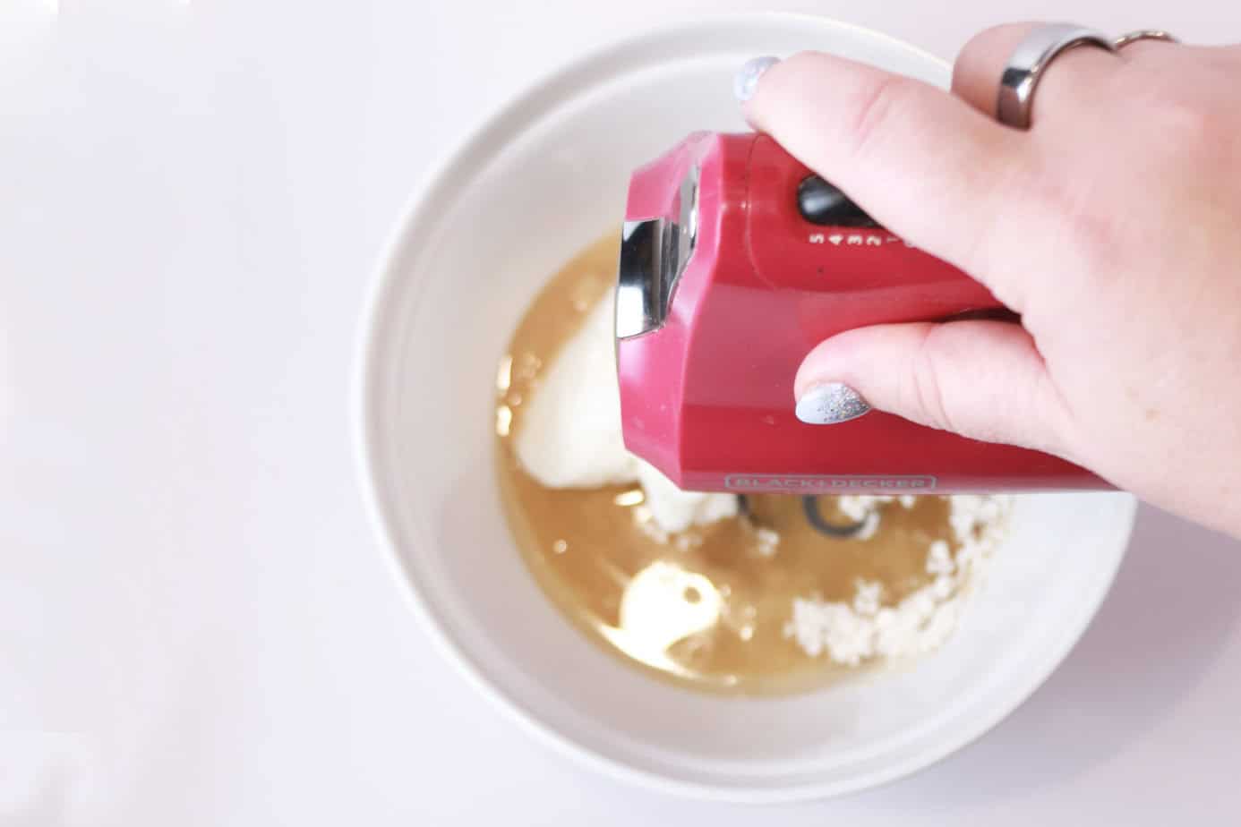 using an electric mixer to mix up cake goop ingredients in a white bowl