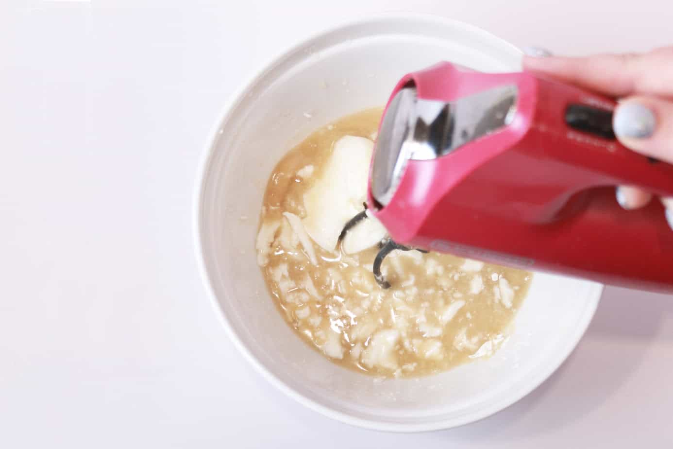 using an electric mixer to mix up cake goop ingredients in a white bowl