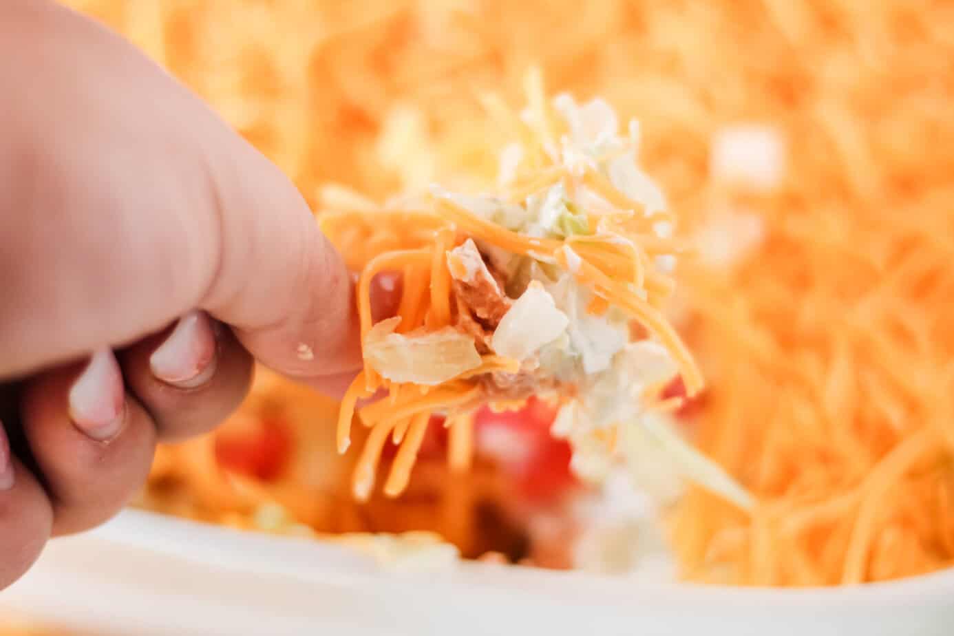a bite of taco dip on a tortilla chip
