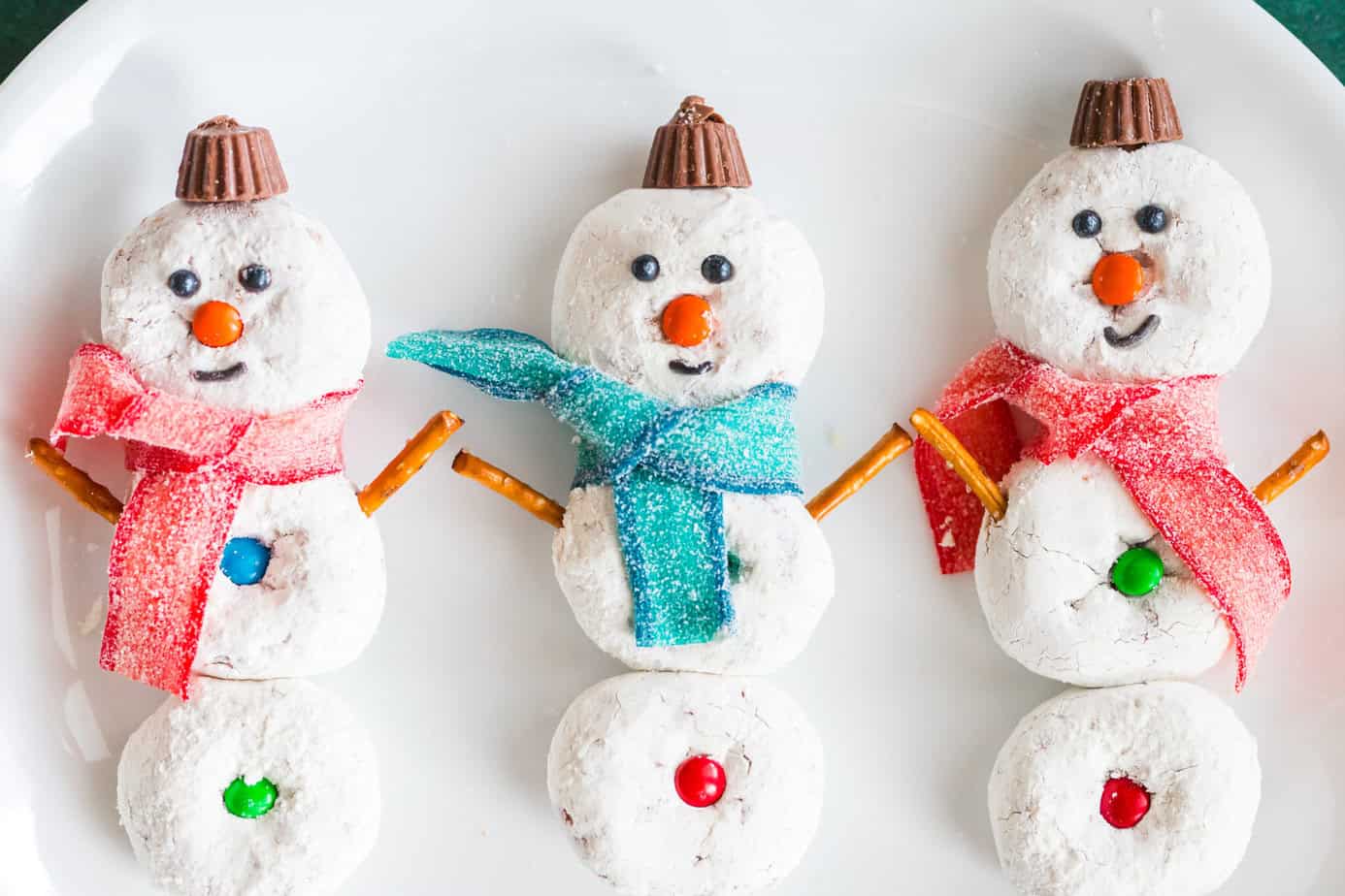 three donut snowmen on a white plate