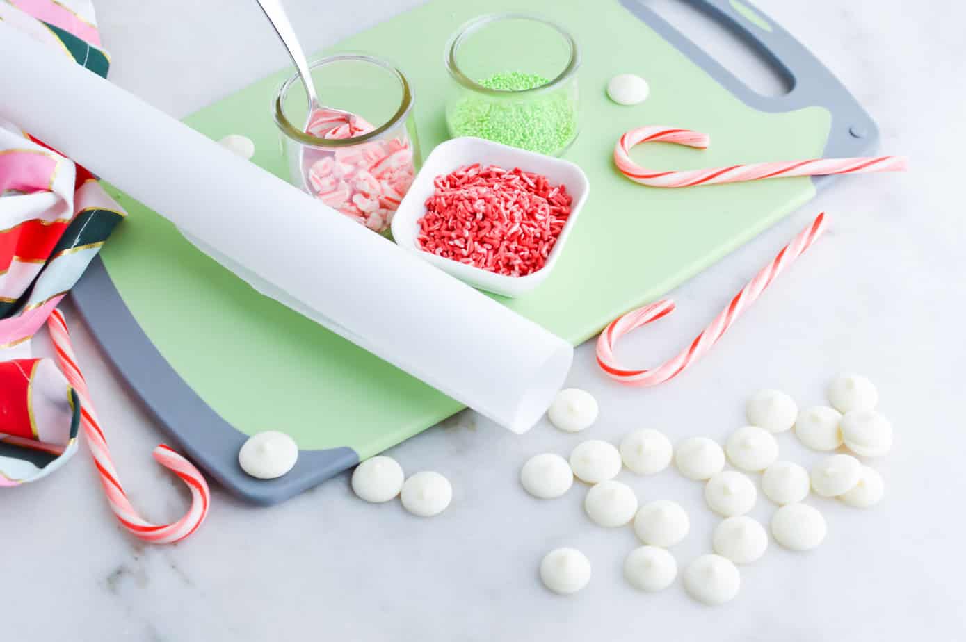 white chocolate peppermint bark ingredients on a cutting board with parchment paper