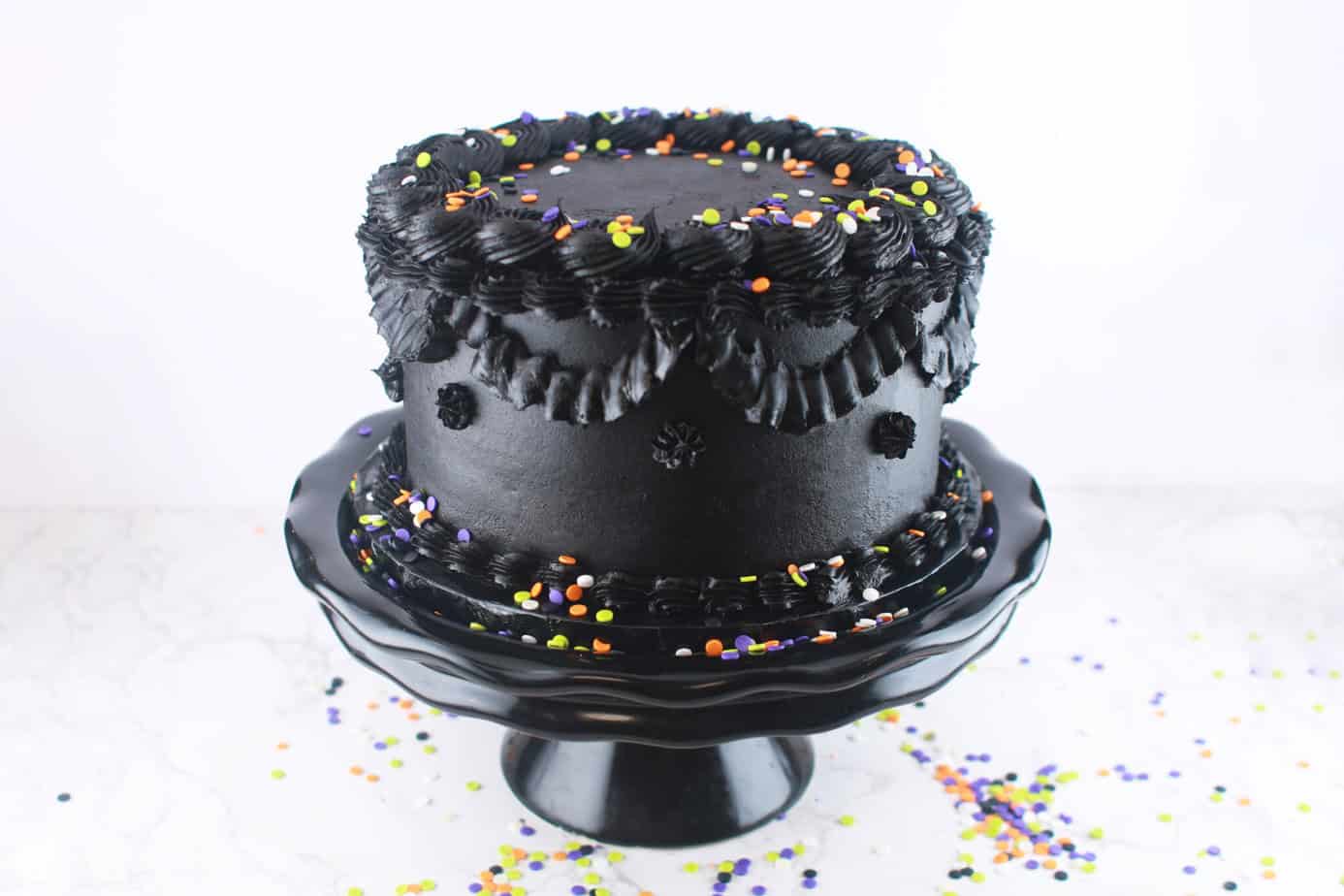Black Halloween Birthday Cake on a black cake stand with sprinkles around it