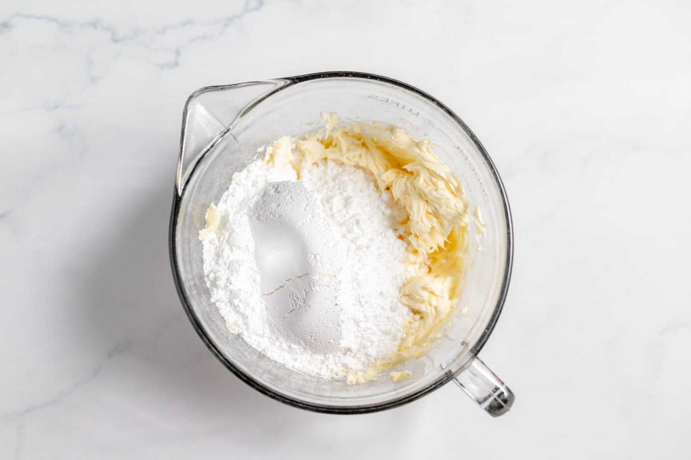 powdered sugar in clear bowl with creamed butter and powdered sugar