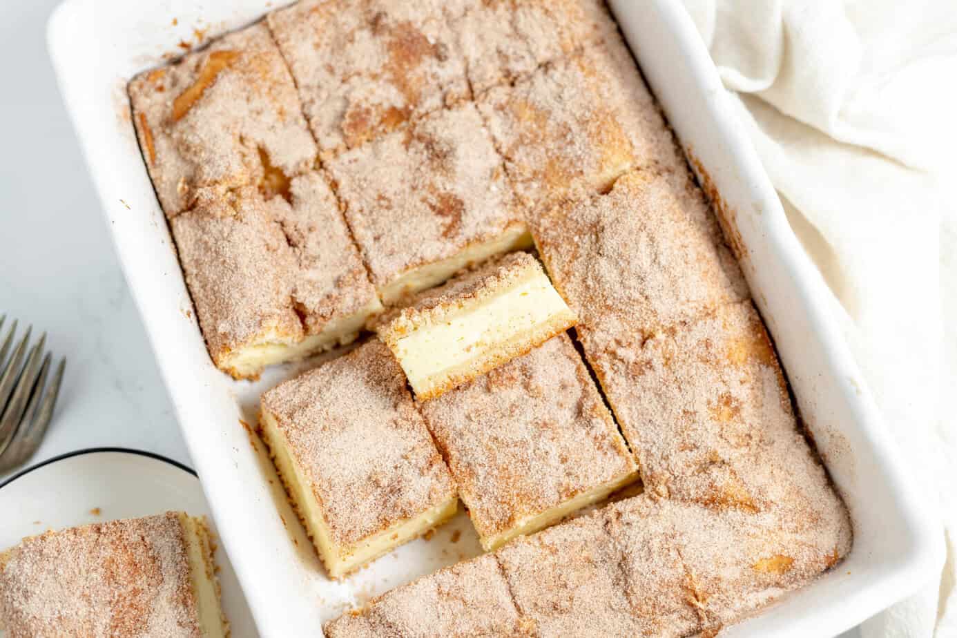 churro cheesecake bars cut into squares in a pan