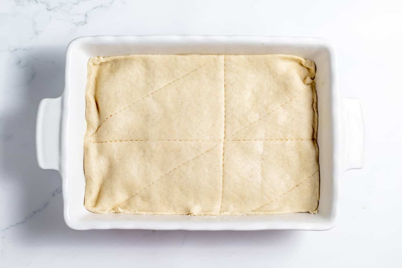top crescent roll dough over cheesecake