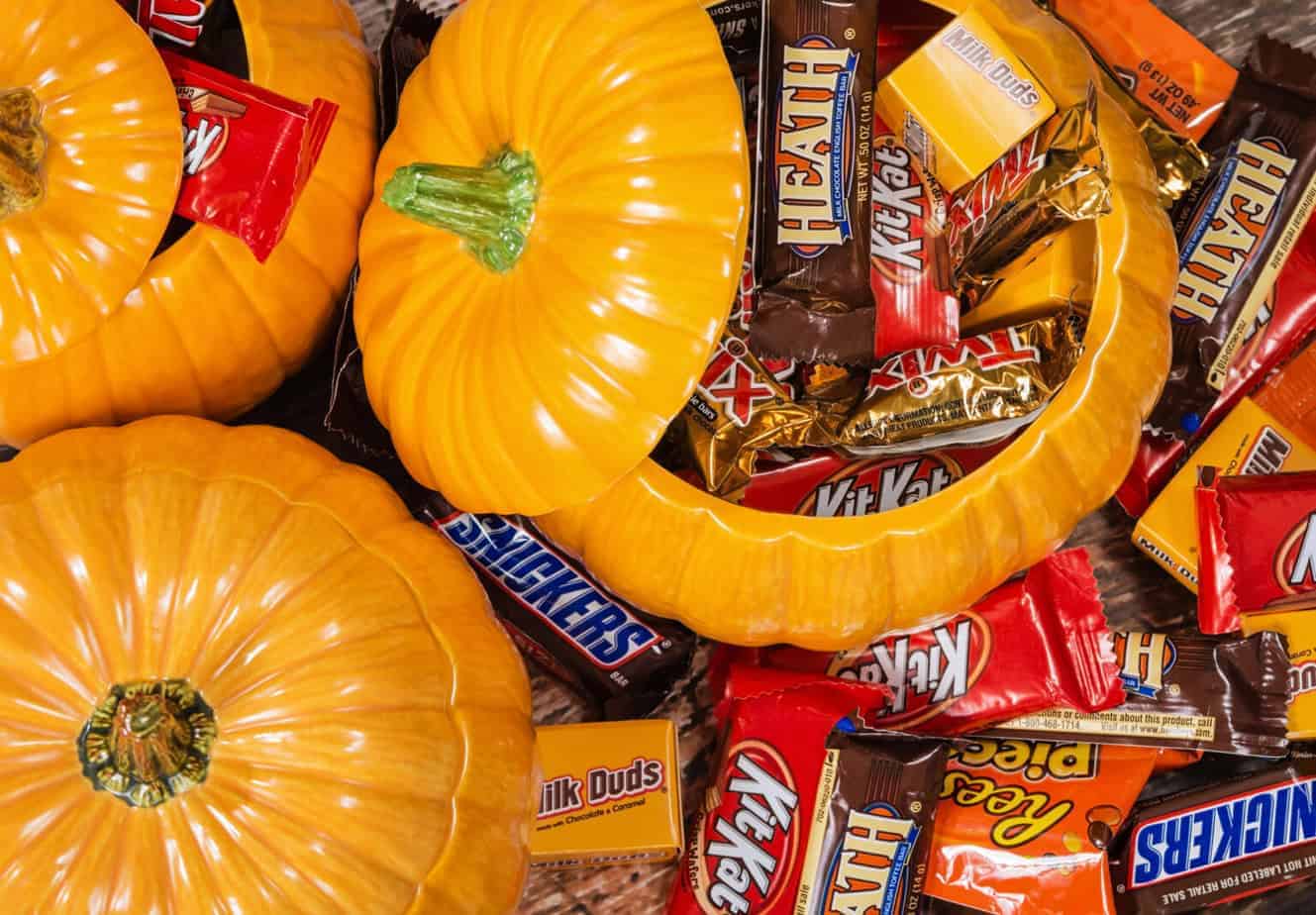a variety of mini candy bars around pumpkins for halloween candy