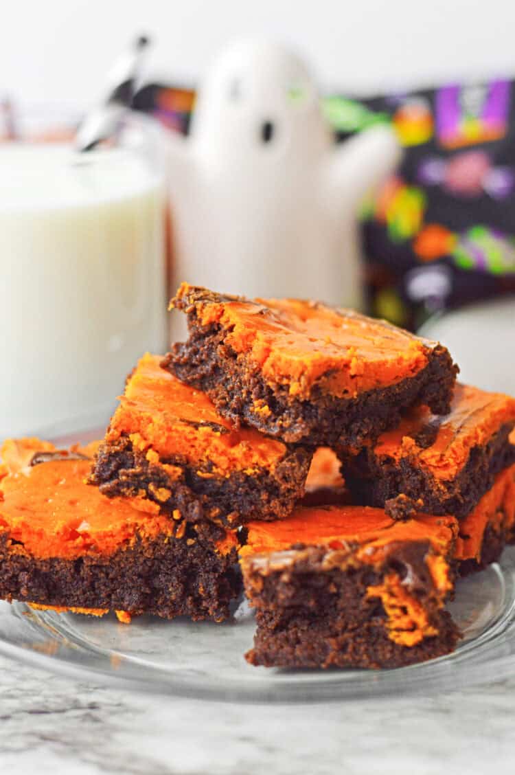 orange and brown halloween brownies on a clear plate
