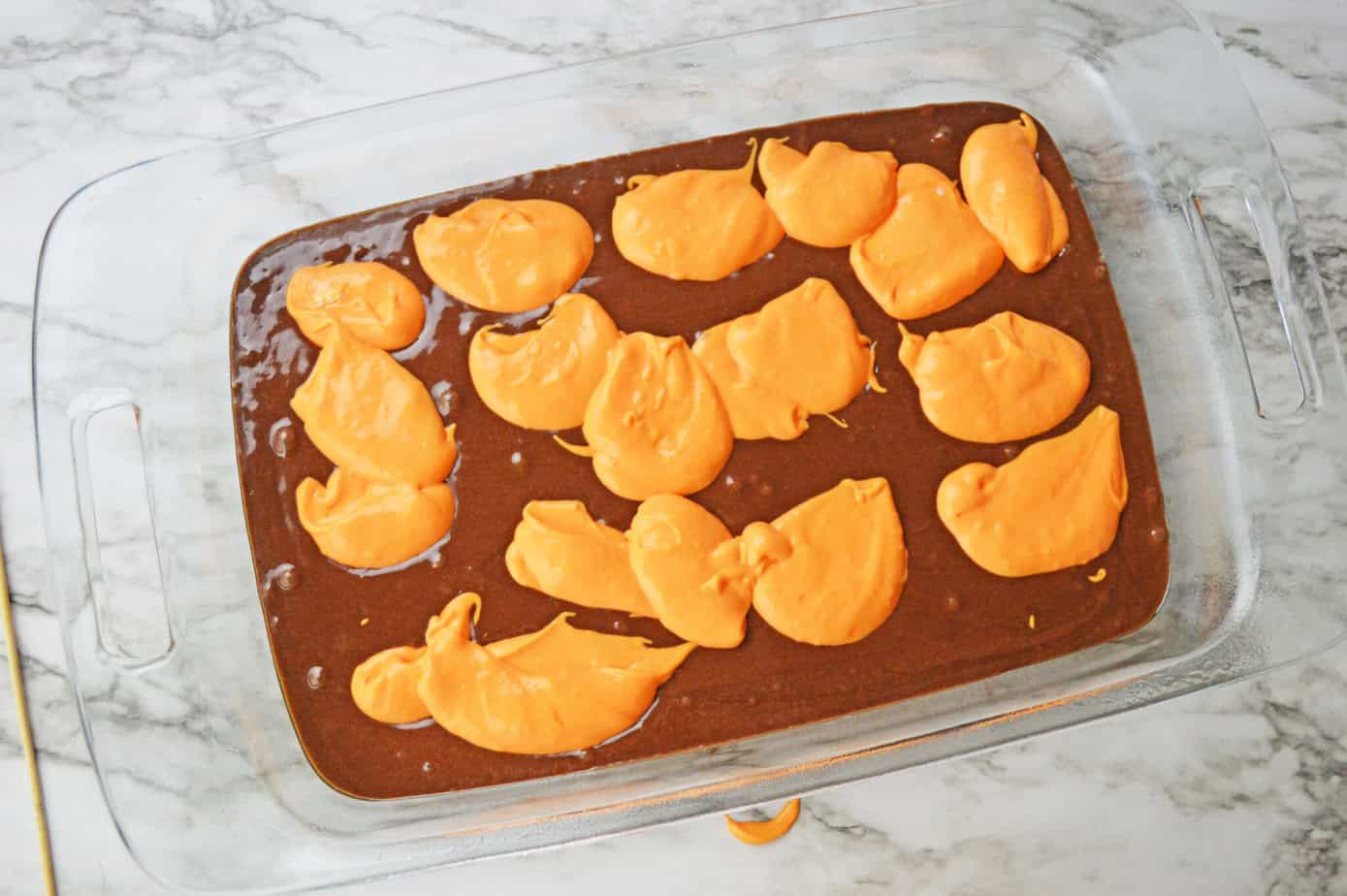 spoonfuls of cheesecake batter in the brownie batter 