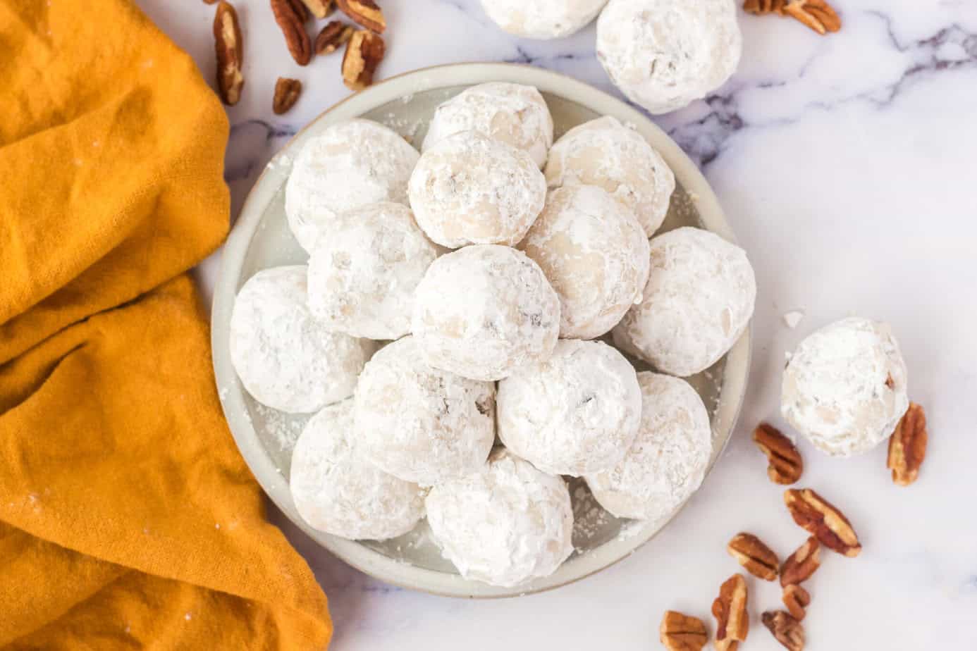 pecan sandies cookies stacked on a white plate
