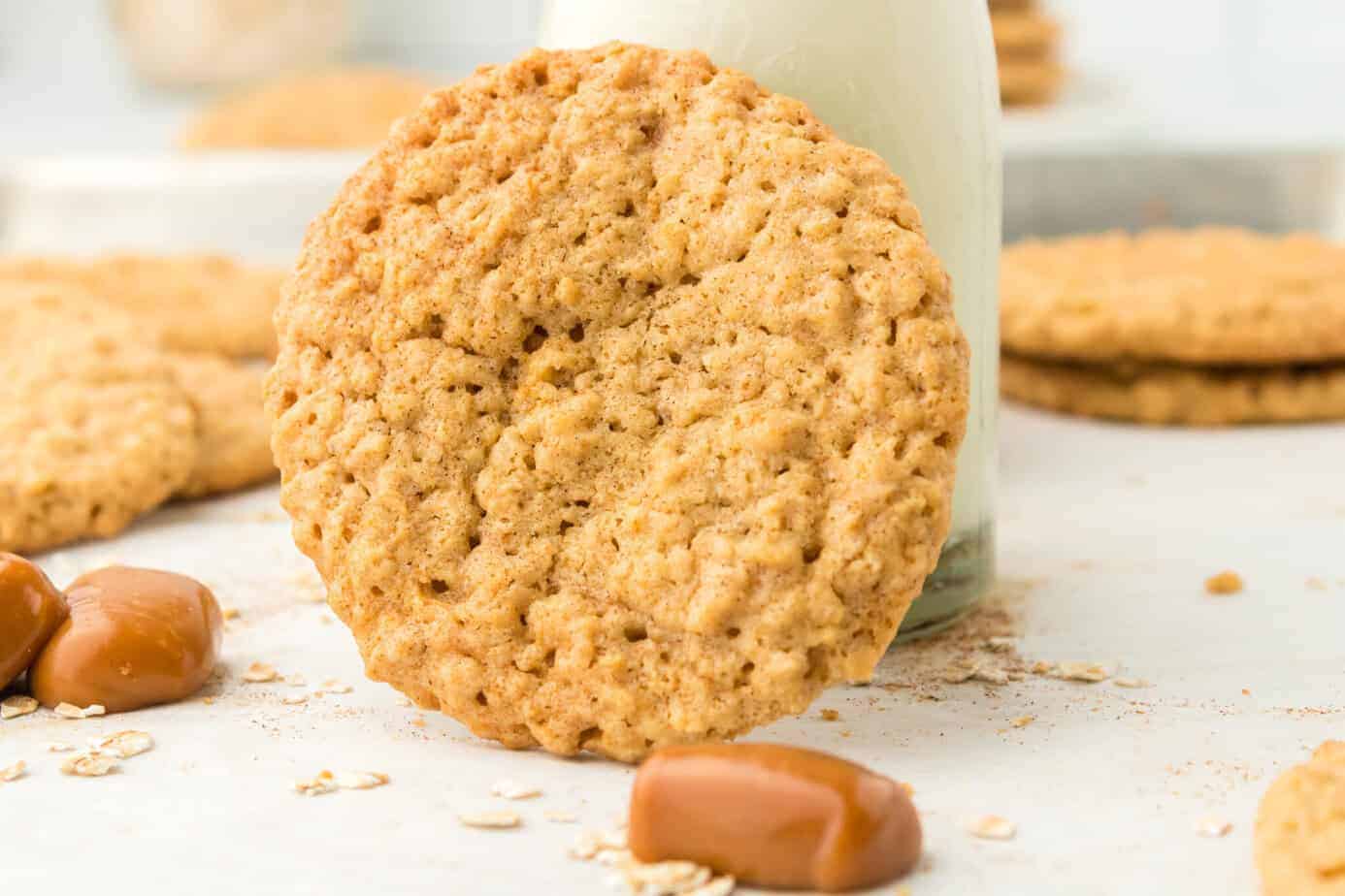 chewy caramel oatmeal cookie leaning on a bottle of milk