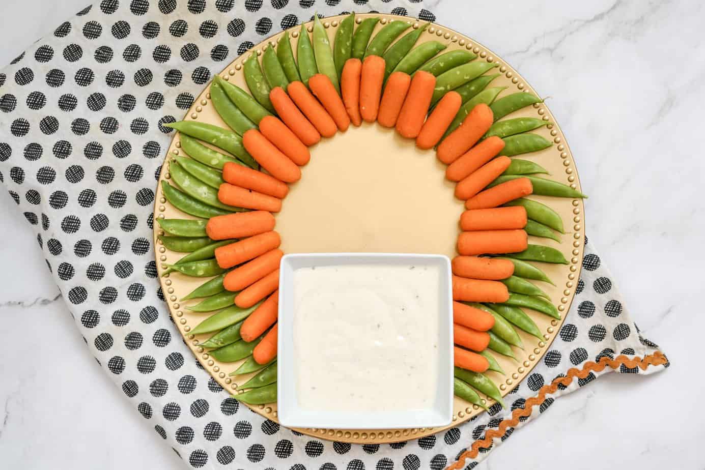 carrots inside the sugar snap peas around the outside of a platter 
