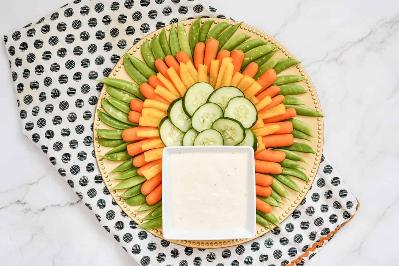 cucumbers in the center plus Yellow bell pepper sticks and carrots inside the sugar snap peas around the outside of a platter 