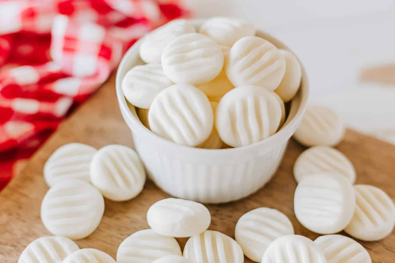 cream cheese mints in a white bowl on a cutting board