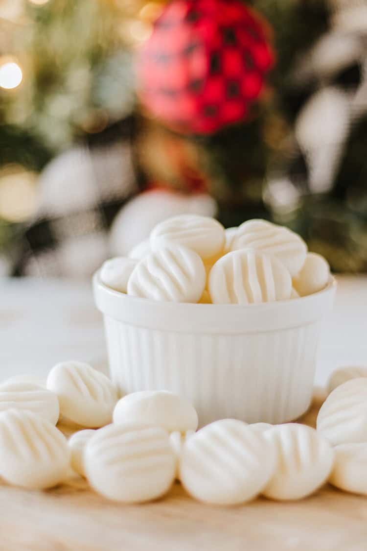 Christmas Cream Cheese Mints in a white bowl with some spilling onto cutting board