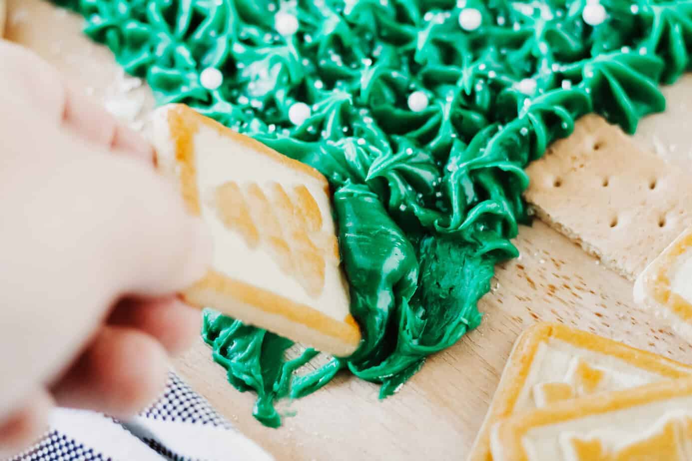 dipping buttercream from the christmas tree frosting board with a cookie