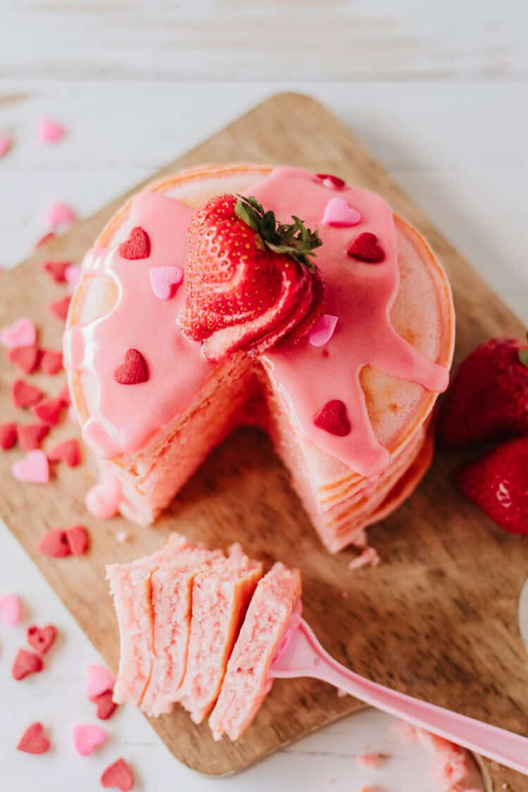 strawberry pancakes with pink syrup, heart sprinkles and fresh strawberries
