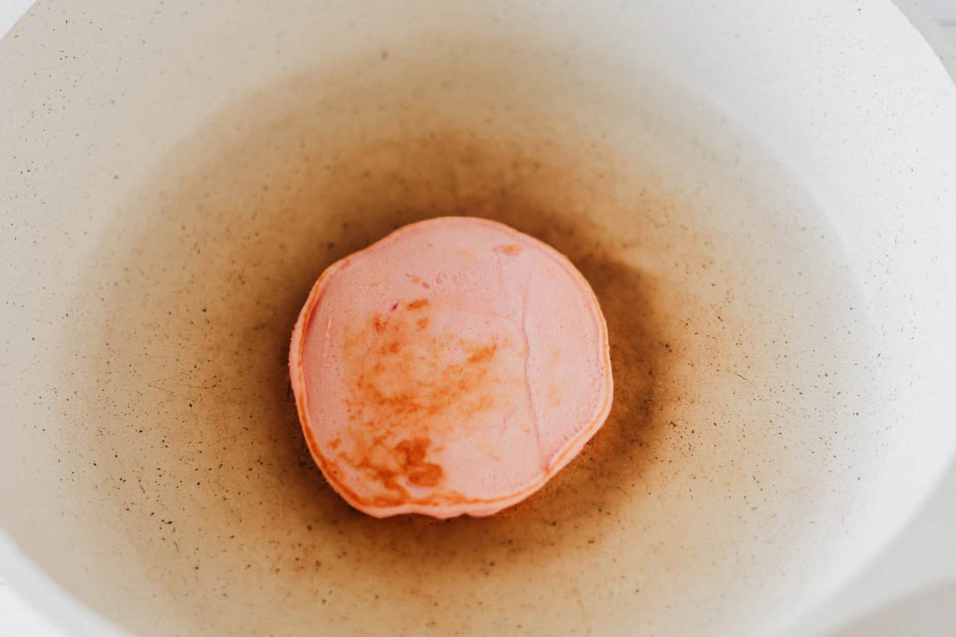 cooking a pink pancake in a skillet