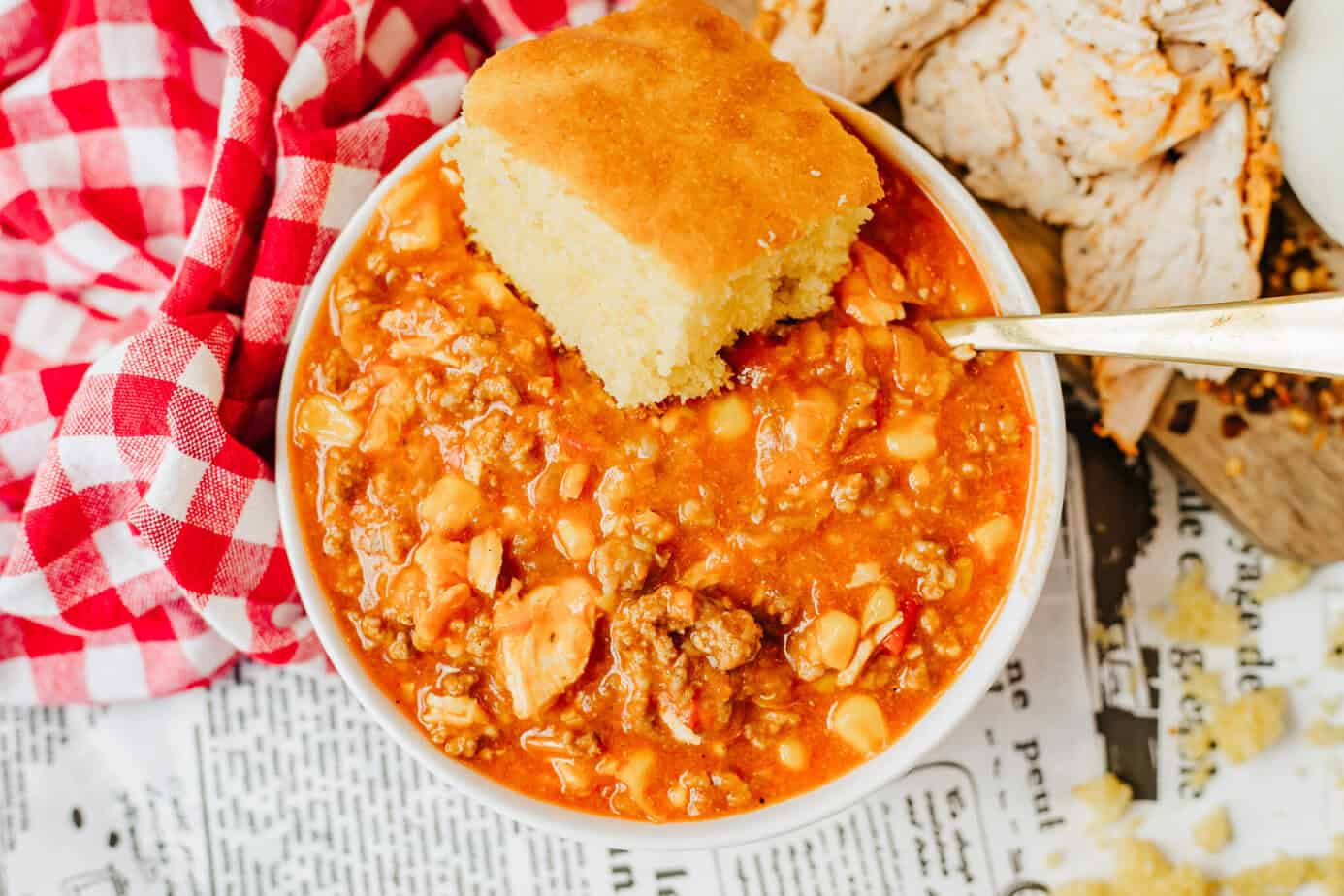 overhead shot of Brunswick Stew in a white bowl with a slice of cornbread on the side
