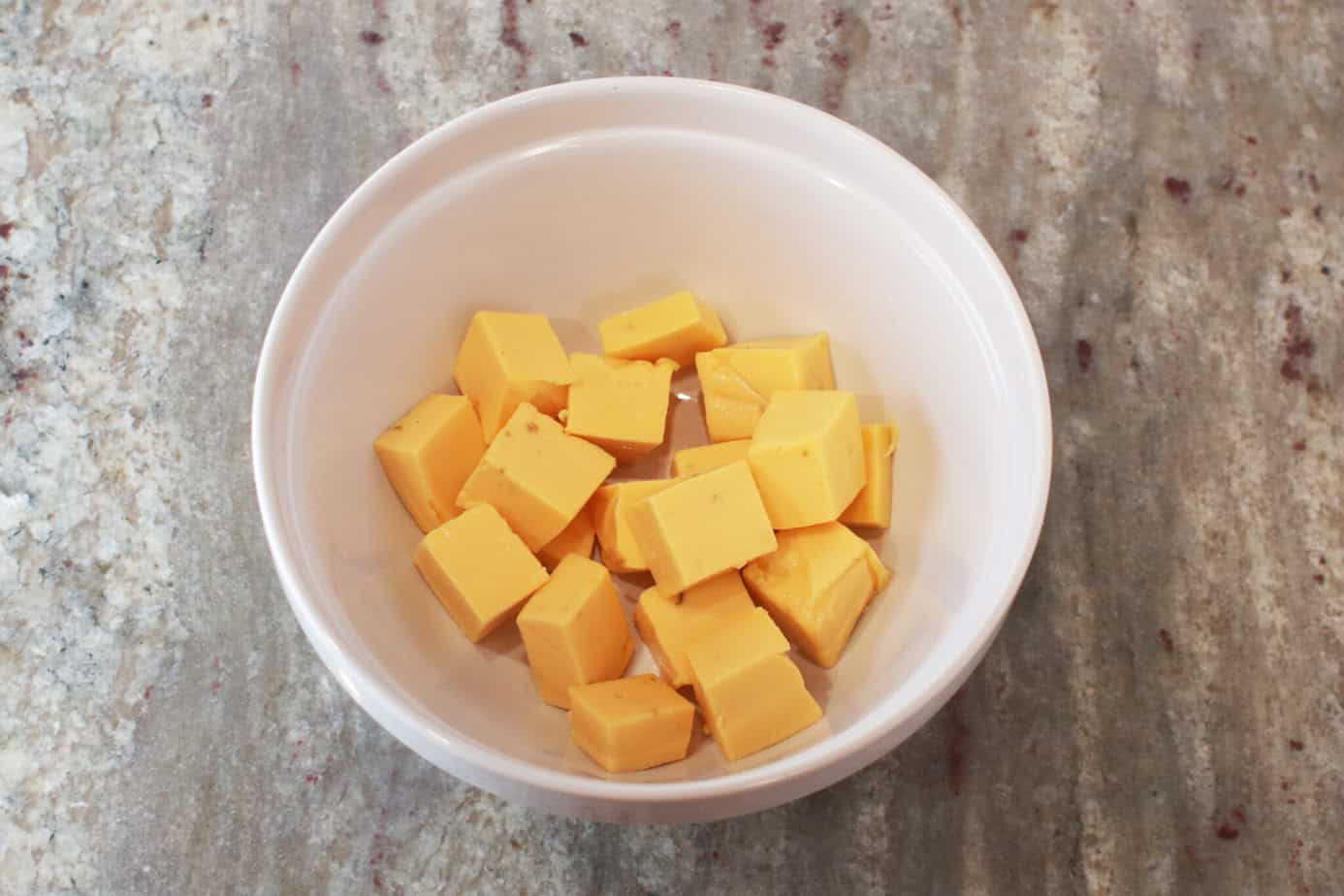 cubed velveeta in white mixing bowl
