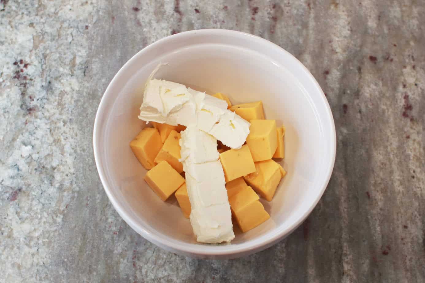 cubed velveeta and cream cheese in white mixing bowl